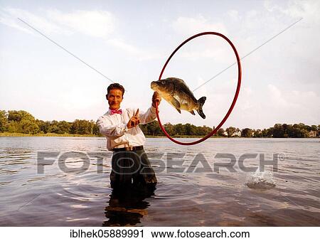 Stock Image - Acrobat, dressage, carp, lake, fish jumps through a hoop, Berlin Germany. Fotosearch