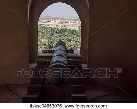 Stock Photograph - Arched window and cannon, palm oasis, view from the fortress Nakhl, Nakhl, Oman, Asia. Fotosearch