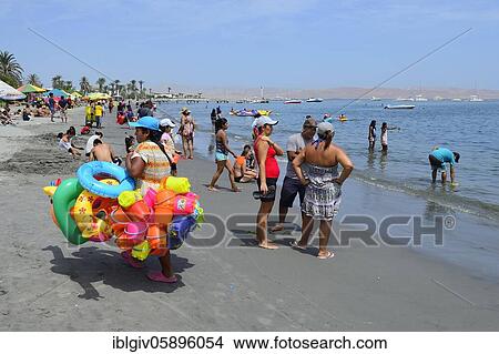 Picture - Beach saleswoman with colorful swimming tires and sand toys, Paracas, Ica region, Peru, South America. Fotosearch