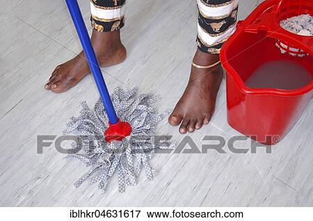 Stock Photo - Black woman cleans the floor, symbol picture for racism, migration, discrimination. Fotosearch