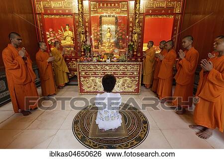 Stock Photograph - Buddhist Sacrifice Ceremony with praying monks and kneeling woman, Wat Mangkon Kamalawat, Chinese Buddhist temple, Chinatown, Pom Prap Sattru Phai, Bangkok, Thailand, Asia. Fotosearch