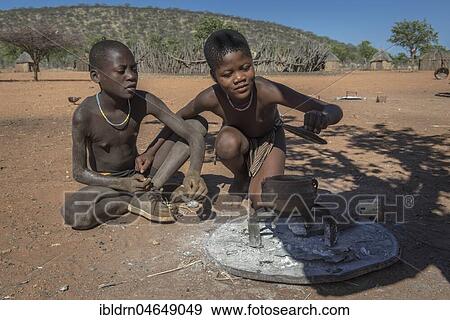 Stock Photo - Children of the Ovahimba or Himba people look curiously into a pot over the fire, Kunene district, Namibia, Africa. Fotosearch