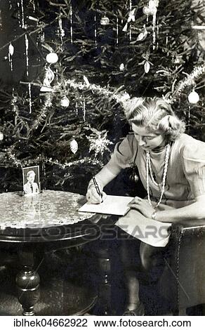 Stock Image - Christmas during World War II, Woman writes a letter in front of Christmas tree, 1940s, Germany, Europe. Fotosearch
