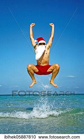 Stock Image - Christmas, Santa Claus jumps in the air, Koh Samui, Thailand, Asia. Fotosearch