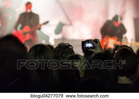 Concertgoer takes a photo with I Phone at the concert of the Swiss band 77 Bombay Street live at Schüür Lucerne, Switzerland, Europe View Large Photo Image Stock Photo - Concertgoer takes a photo with I Phone at the concert of the Swiss band 77 Bombay Street live at Schüür Lucerne, Switzerland, Europe. Fotosearch