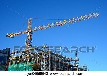 Stock Image - Crane against a blue sky on a construction site, Ystad, Scania, Sweden, Europe. Fotosearch