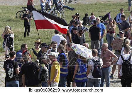 Stock Photo - Demo against Corona rules on the Rhine meadows, man with forbidden Reich war flag, surrounded by people, Düsseldorf, North Rhine-Westphalia, Germany, Europe. Fotosearch