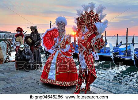 Stock Photograph - Disguised couple with Venetian masks at the lagoon, behind island San Giorgio, carnival in Venice, Italy, Europe. Fotosearch