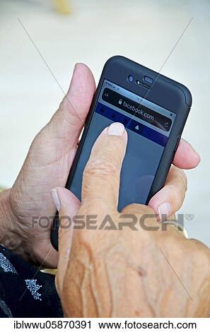 Stock Image - Elderly woman holding a smartphone in her hand. Fotosearch
