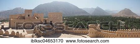 Stock Image - Fortress Nakhl with round tower and battlements, at the back Hajar Mountains, panoramic view, Nakhl, Oman, Asia. Fotosearch