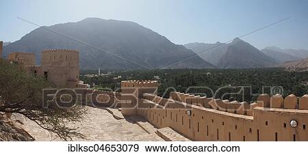 Stock Photo - Fortress Nakhl with round tower and battlements, at the back Hajar Mountains, panoramic view, Nakhl, Oman, Asia. Fotosearch