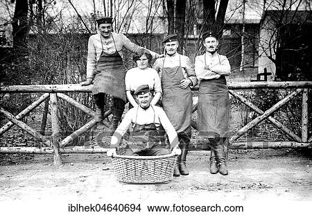 Picture - Four uniformed men and one woman pose in front of fence, 1910s, exact place unknown, Germany, Europe. Fotosearch