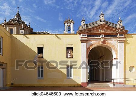 Stock Image - Gigantic figure looking out of a window, installation Alicia, artwork 2009 by Cristina Lucas, Monasterio de la Cartuja, CAAC, Centro Andaluz de Arte Contemporáneo, Seville, Andalusia, Spain, Europe. Fotosearch