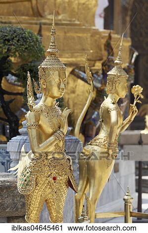 Stock Image - Gilded statues, mythical Buddhist figures, in front Theppaksi, half woman, half bird, Phra Kaew, Ko Ratanakosin, Bangkok, Thailand, Asia. Fotosearch