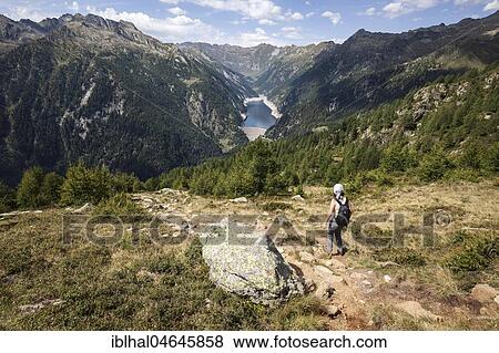 Hiker on the hiking trail from Alpe Corte del Sasso to Alpe Corte di Mezzo, in the back Sambuco, Lago di Sambuco, Fusio, Lavizzara, Canton Ticino, Switzerland, Europe View Large Photo Image Stock Photo - Hiker on the hiking trail from Alpe Corte del Sasso to Alpe Corte di Mezzo, in the back Sambuco, Lago di Sambuco, Fusio, Lavizzara, Canton Ticino, Switzerland, Europe. Fotosearch