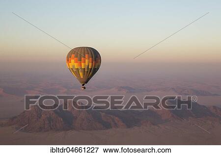 Hot-air balloon above an arid plain and isolated mountain ridges, at dawn, Namib Desert, aerial view from a second balloon, NamibRand Nature Reserve, Namibia, Africa View Large Photo Image Stock Photo - Hot-air balloon above an arid plain and isolated mountain ridges, at dawn, Namib Desert, aerial view from a second balloon, NamibRand Nature Reserve, Namibia, Africa. Fotosearch