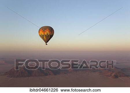 Hot-air balloon above an arid plain and isolated mountain ridges, at dawn, Namib Desert, aerial view from a second balloon, NamibRand Nature Reserve, Namibia, Africa View Large Photo Image Stock Photograph - Hot-air balloon above an arid plain and isolated mountain ridges, at dawn, Namib Desert, aerial view from a second balloon, NamibRand Nature Reserve, Namibia, Africa. Fotosearch