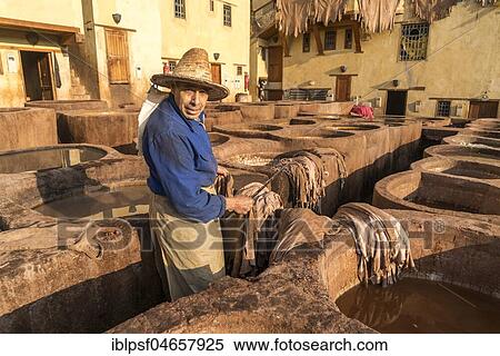 Stock Photography - Leather tanners on tanks with paint for dyeing leather, dyeing, tannery Tannerie Chouara, tanner and dyeing district Fes el Bali, Fez, Morocco, Africa. Fotosearch
