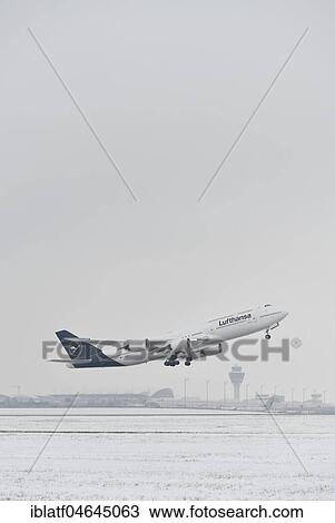 Stock Image - Lufthansa Boeing B747-800, take-off in snow with tower in the background, Munich Airport, Upper Bavaria, Germany, Europe. Fotosearch