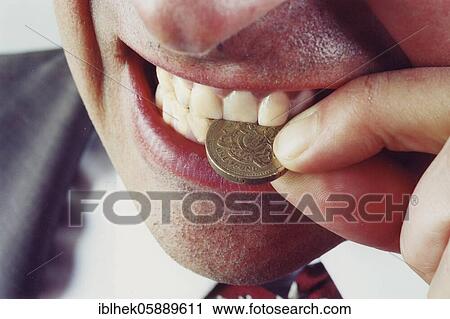 Stock Image - Man bites into a British pound, Currency, Berlin, Germany, Europe. Fotosearch