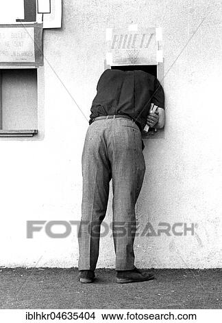 Picture - Man looking through a small window of a ticket sale, between 50s and 60s, exact place unknown, France, Europe. Fotosearch