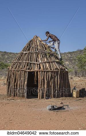 Man of the people of Ovahimba or Himba builds on the roof of a wooden hut, Kunene district, Namibia, Africa View Large Photo Image Stock Image - Man of the people of Ovahimba or Himba builds on the roof of a wooden hut, Kunene district, Namibia, Africa. Fotosearch