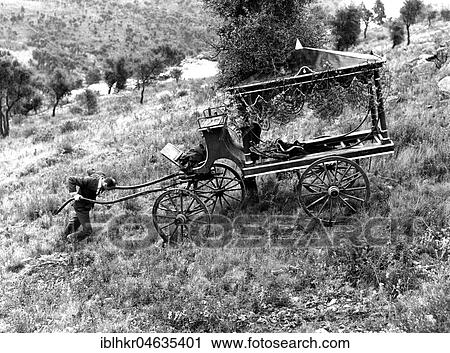 Stock Image - Man pushes a coffin carriage up the slope, between 50s and 60s, exact place unknown, France, Europe. Fotosearch