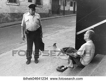 Picture - Man shows policeman his foot, 1960s, Berlin, Germany, Europe. Fotosearch