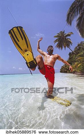 Stock Photograph - Man with fins and diving goggles on the beach, Maldives, Asia. Fotosearch