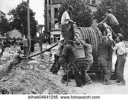Stock Photograph - Men with huge cable reel on construction site, 1960s, Berlin, Germany, Europe. Fotosearch