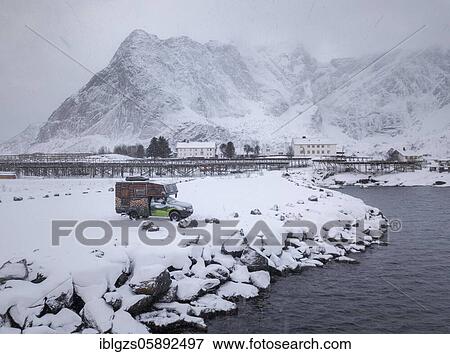 Stock Photo - Motorhome painted as a mountain hut in snowfall at the parking lot in front of a fjord, Reine, Nordland, Lofoten, Norway, Europe. Fotosearch