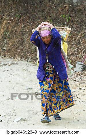 Stock Photo - Old Nepalese woman carrying stones for road construction on her back, Dhampus Mountain village, Nepal, Asia. Fotosearch