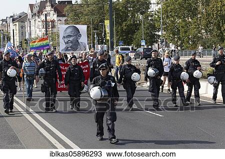 Stock Image - Police marches in front of demonstration march with portrait of Mahatma Gandhi, Demo against Corona Rules, Düsseldorf, North Rhine-Westphalia, Germany, Europe. Fotosearch