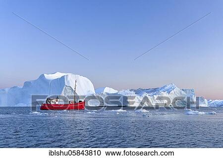 Stock Image - Red boat in front of icebergs at the blue hour, Icefjord, UNESCO World Natural Heritage, Disko Bay, Ilulissat, West Greenland, Greenland, North America. Fotosearch
