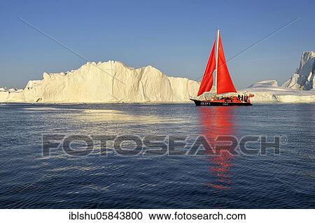 Stock Image - Red sailing boat in front of icebergs, Icefjord, UNESCO World Heritage, Disko Bay, Ilulissat, West Greenland, Greenland, North America. Fotosearch