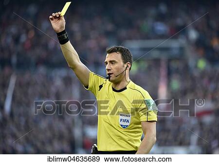 Stock Photo - Referee Felix Zwayer gesticulates and shows yellow card as warning, Mercedes-Benz Arena, Stuttgart, Baden-Württemberg, Germany, Europe. Fotosearch