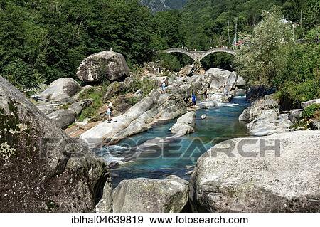 Rock formations, bathing people at Verzasca near Lavertezzo, in the back the Roman bridge Ponte dei Salti, Verzascatal, Valle Verzasca, Canton Ticino, Switzerland, Europe View Large Photo Image Stock Photo - Rock formations, bathing people at Verzasca near Lavertezzo, in the back the Roman bridge Ponte dei Salti, Verzascatal, Valle Verzasca, Canton Ticino, Switzerland, Europe. Fotosearch