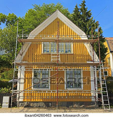Stock Image - Schwedenhaus, gelb und weiss angestrichen, abblatternde Farbe, mit Baugerust, Mariefred, Strangnas, Sodermanlands Lan, Schweden, Europa. Fotosearch
