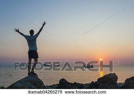 Silhouette eines jungen Mannes, Boot im Meer bei Sonnenuntergang vor kleinen Inseln, Insel Koh Samui, Golf von Thailand, Thailand, Asien View Large Photo Image Stock Photo - Silhouette eines jungen Mannes, Boot im Meer bei Sonnenuntergang vor kleinen Inseln, Insel Koh Samui, Golf von Thailand, Thailand, Asien. Fotosearch