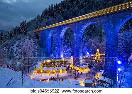 Stock Image - Snowy Christmas market under a railway viaduct, illuminated, Ravennaschlucht, Höllental near Freiburg im Breisgau, Black Forest, Baden-Württemberg, Germany, Europe. Fotosearch