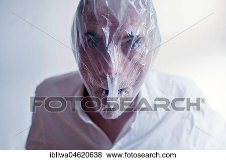 Stock Photo - Symbol picture Psychosis, madness, face of a man behind plastic foil. Fotosearch
