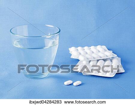 Stock Image - Tabletten mit Blister-Verpackung und ein Glas Wasser. Fotosearch
