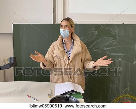 Stock Photo - Teacher with thick winter jacket and face mask in classroom teaching, gestures, corona crisis, Stuttgart, Baden-Württemberg, Germany, Europe. Fotosearch