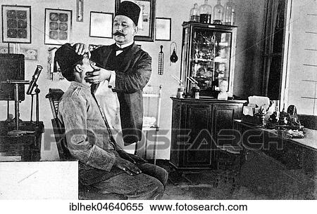 Stock Photography - The Arab doctor Dr. Nikolaki examines the eyes of a patient, ca. 1910, Beirut, Lebanon, Asia. Fotosearch