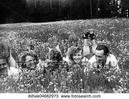 Stock Image - Three women and two men lying in a meadow of flowers, 1930s, Germany, Europe. Fotosearch