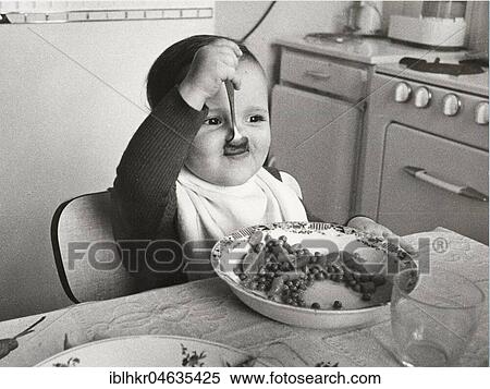 Stock Photography - Toddler eats with spoon, between 50s and 60s, exact place unknown, France, Europe. Fotosearch