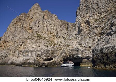 Picture - Tourist boat entering the sea cave Grotta Perciata, island of Marettimo, Egadic Islands, Italy, Europe. Fotosearch