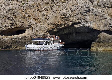 Stock Image - Tourist boat entering the sea cave Grotta Perciata, island of Marettimo, Egadic Islands, Italy, Europe. Fotosearch