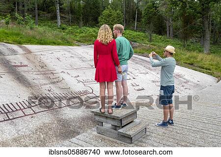 Stock Image - Tourists, rock carvings, open air museum Vitlycke, Tanumshede, Västra Götalands län, Sweden, Europe. Fotosearch