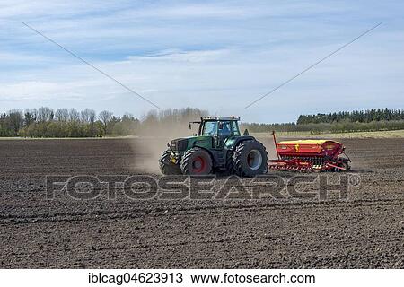 Stock Image - Tractor with seed drill working a field in spring, Syddanmark, Denmark, Europe. Fotosearch